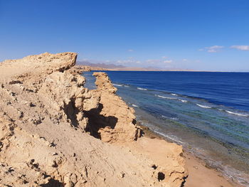 Rock formation on beach against sky