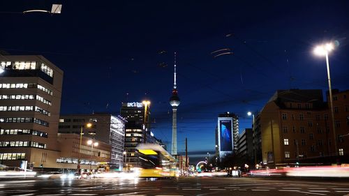 Illuminated city street and buildings against sky at night