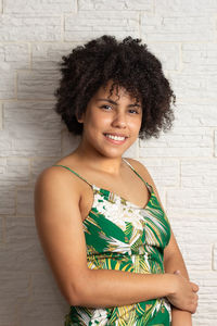 Portrait of young woman standing against wall