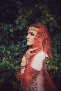 Portrait of young woman standing against plants