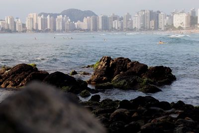 Scenic view of sea by cityscape against sky