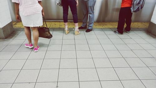 Low section of people standing on tiled floor