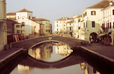 Canal in city against sky