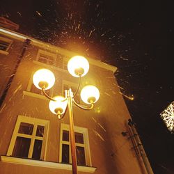 Low angle view of illuminated street light against building