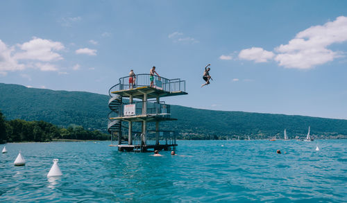 People jump into lake annecy from a diving board