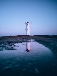 Lighthouse amidst buildings against clear sky