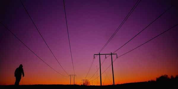 Silhouette of electricity pylon against sky during sunset