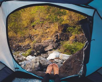 Low section of woman relaxing in tent at forest