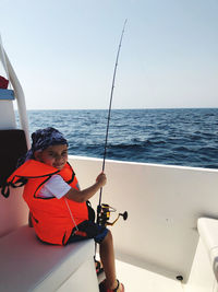 Man sitting in boat against sky