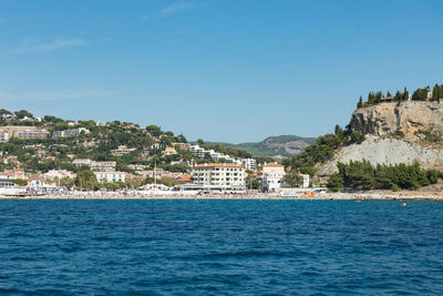 Buildings by sea against blue sky