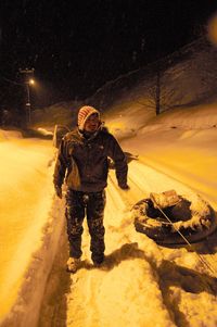 Full length of man standing on snow covered road at night