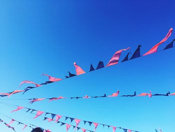 Low angle view of bunting against clear blue sky