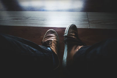 Low section of man wearing shoes on hardwood floor
