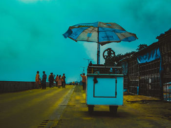 People on road against blue sky