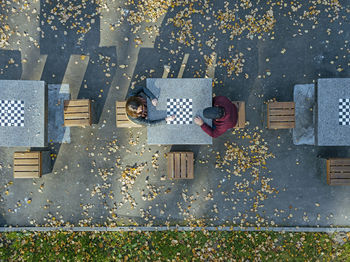 Boyfriend playing chess with girlfriend at table in park during autumn