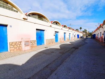 Street amidst buildings against blue sky