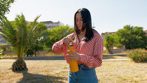 Rear view of woman with arms raised standing against trees