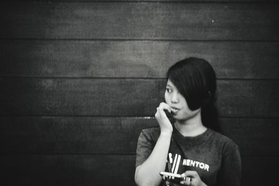 Portrait of young woman looking away against wall