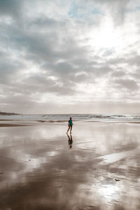Full length of boy running at beach against sky