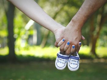 Cropped image of woman and man hands holding baby booties