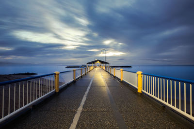 Footbridge over sea against sky during sunset