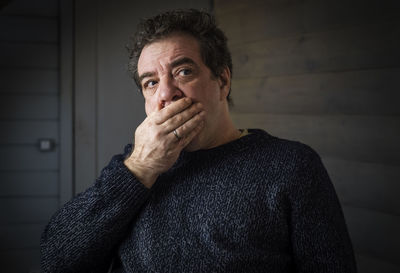 Portrait of sad man standing against wall at home