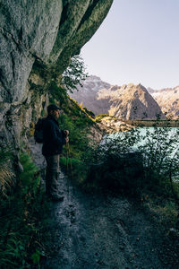 Rear view of man standing on rock by mountain