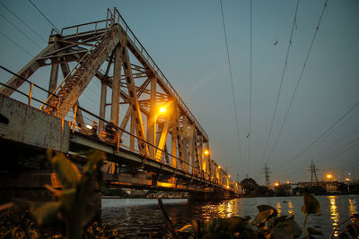 Illuminated bridge over river in city against sky