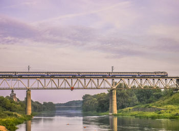 Train on bridge over river against sky