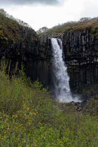 Scenic view of waterfall in forest against sky