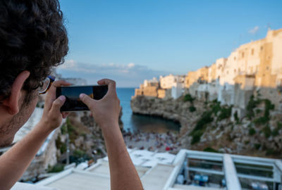 Cropped hand of woman photographing against sky