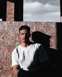 Portrait of young man standing against wall