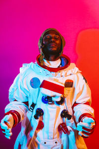 Portrait of young man standing against colored background