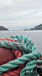 Close-up of rope tied on bollard against sea