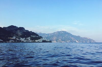 Scenic view of sea and mountains against blue sky