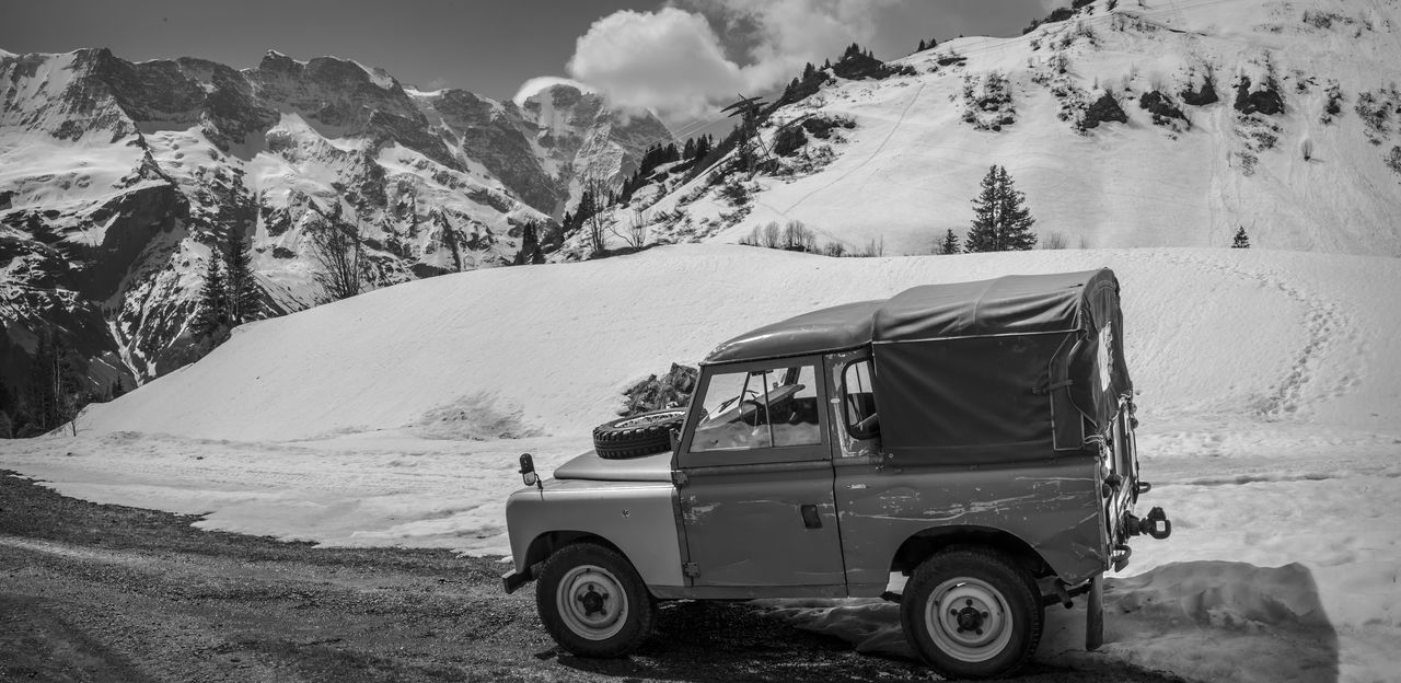 transportation, snow, mode of transportation, mountain, car, travel, landscape, motor vehicle, environment, mountain range, cold temperature, scenics - nature, vehicle, nature, off-roading, winter, land vehicle, adventure, snowcapped mountain, black and white, land, beauty in nature, road, journey, monochrome photography, day, sky, holiday, monochrome, vacation, travel destinations, outdoors, non-urban scene