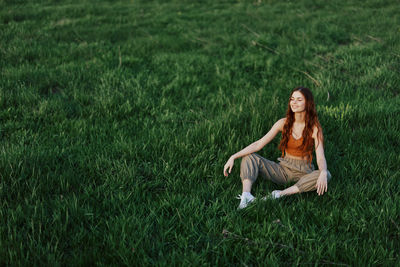 Full length of woman sitting on grassy field
