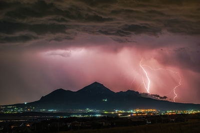 Lightning over illuminated cityscape at night