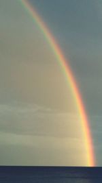 Scenic view of rainbow over sea against sky