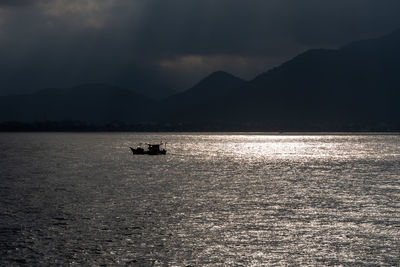 Silhouette boat sailing on sea against sky