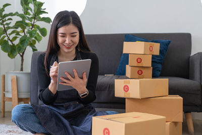 Young woman using digital tablet while sitting on sofa at home