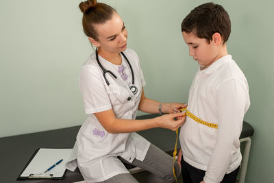 Upset boy during waistline measurement at a nutritionists appointment.