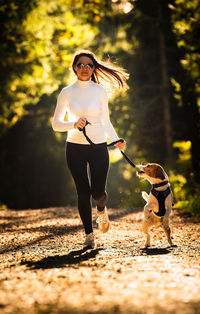 Full length of woman jogging with dog at park