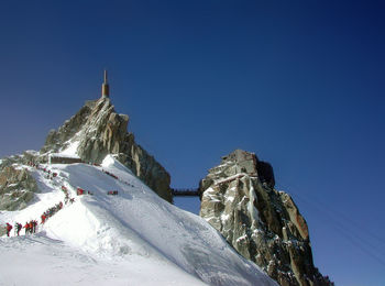 Low angle view of snowcapped mountain against clear blue sky