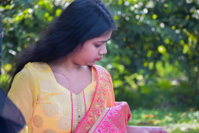 Young woman looking away while sitting on plant