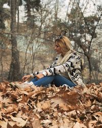 Young woman sitting on tree in forest