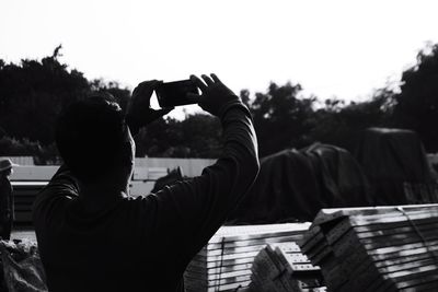 Rear view of man photographing from mobile phone outdoors