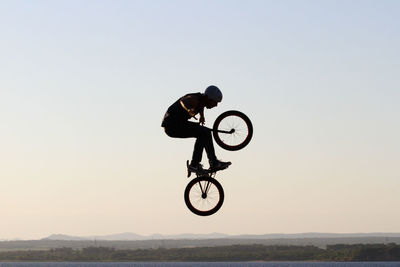 Man riding bicycle on street against sky