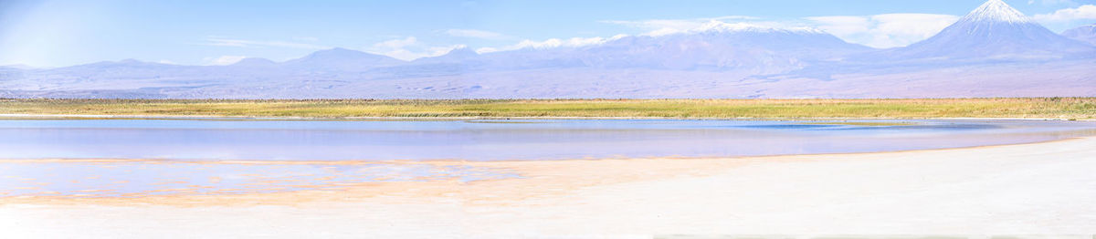 Scenic view of lake by snowcapped mountains against sky