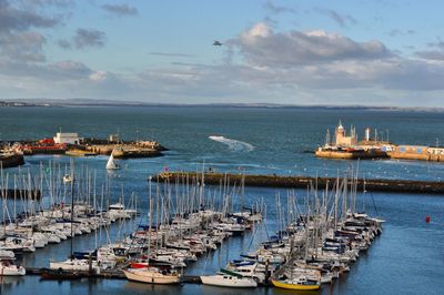 High angle view of sailboats moored at harbor against sky